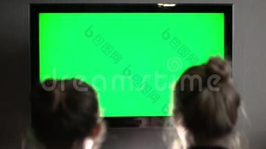 两个年轻的金发金发金发女郎看着绿色的电视屏幕，突然转过头来